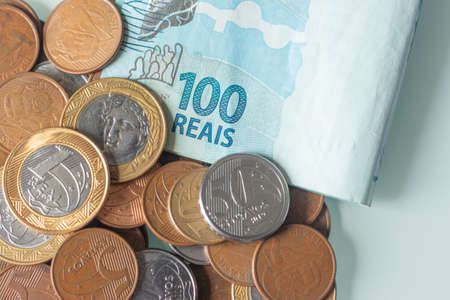 top view several copies of Brazilian coins and one hundred reais banknote