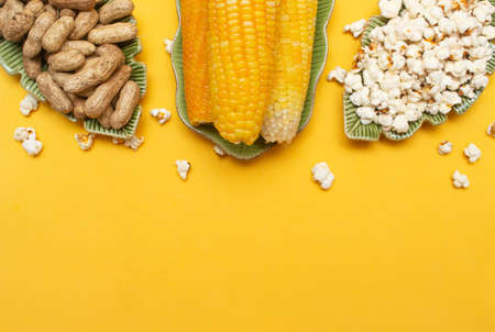 brazilian june party snacks like popcorn, peanuts and corn on a yellow background