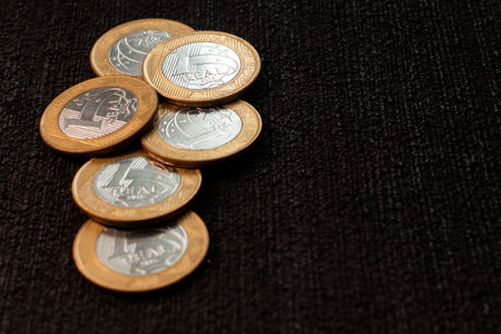 several coins of brazilian money on the black background