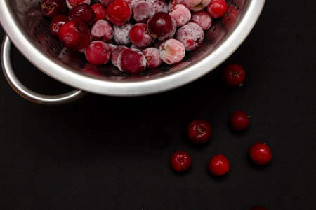 bowl full of frozen and fresh acerolas and black backgroundの写真素材