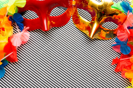 carnival masks on a black and white striped background and colorful flowersの写真素材