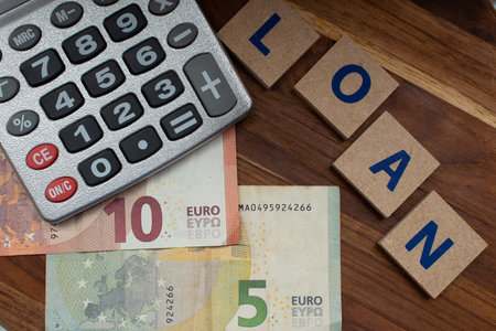 euro banknotes and various coins around a calculator - written: loan