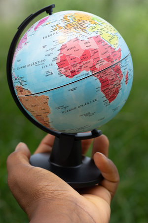 hand holding a terrestrial globe with green backgroundの写真素材