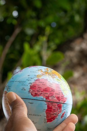 hand holding a terrestrial globe with green texture background showing Africa continentの写真素材