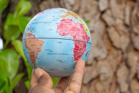 hand holding a terrestrial globe with wooden texture backgroundの写真素材