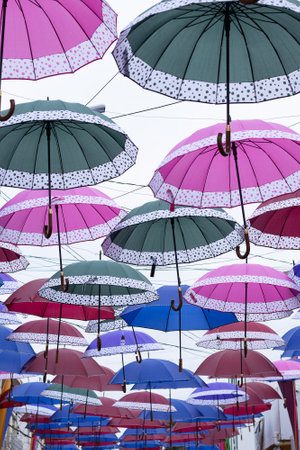 several colorful parasols hanging on a cloudy dayの写真素材