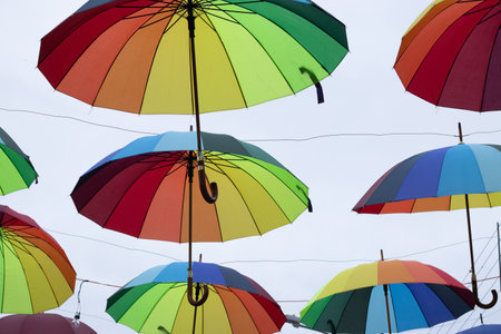 several colorful parasols hanging on a cloudy dayの写真素材