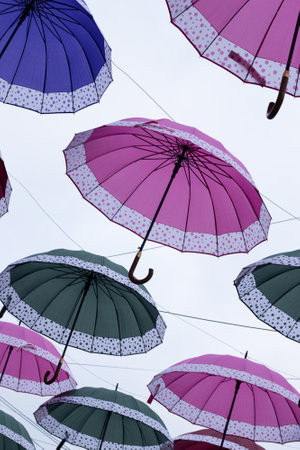 several colorful parasols hanging on a cloudy dayの写真素材