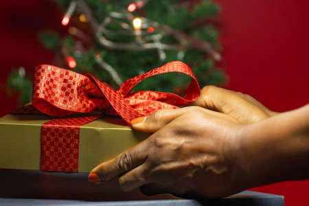 hand holding on gift box with a Christmas tree in backgroundの写真素材