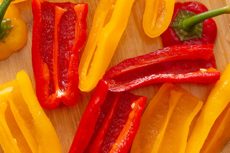 sliced and fresh sliced yellow and red peppers on wooden table