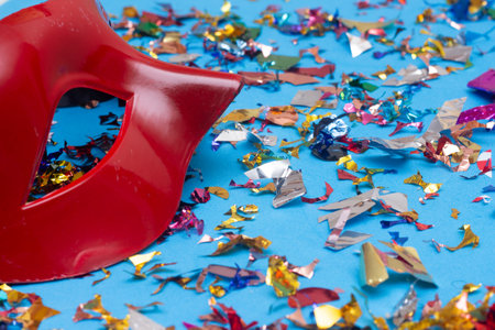 Colorful confetti and red carnival mask on blue background.の写真素材