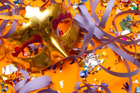 Mardi Gras mask with confetti and streamers on orange backgroundの写真素材