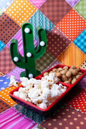 Popcorn in a red bowl with cactus on colorful tableclothの写真素材