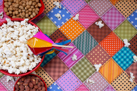 Popcorn and nuts in colorful bowls on a checkered backgroundの写真素材