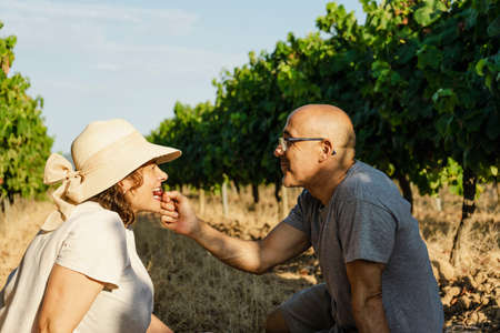 Man giving a grape to his girl at a peaceful picnic
