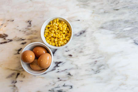 Bowl of corn and eggs on a marble tableの写真素材