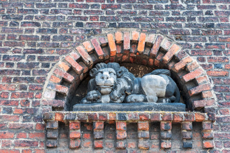 Ornamental sculpture located in Tower in Nysa, Poland. Figure of lion placed in medieval gate tower. Red and brown brick wall.のeditorial素材