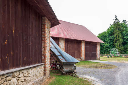 old agricultural machine against the backdrop of a beautiful large barnの写真素材