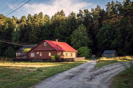 A beautiful sunset in a small village bordering the forest. A small country house illuminated by the sun. KrasnobrÃ³d, Polandの写真素材