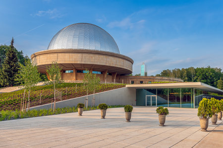 Modern entrance to the Silesian planetarium after renovation. Aluminum panels on the dome of the planetarium shining in the light of the setting sun. Observation tower in the background.のeditorial素材