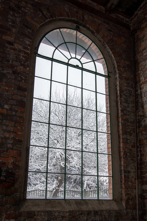 Big, arcade window with muntins in a shabby, brick wall. industrial interior. Winter scenery outside the window.の写真素材