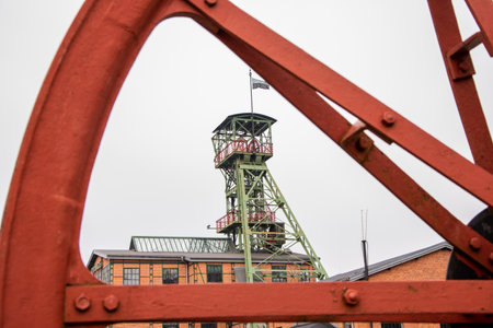 Zabrze, Silesia, Poland - Febuary 11th, 2023: Buildings from former mine "Concordia", shaft tower "Maciej", seen through big flywheel.のeditorial素材
