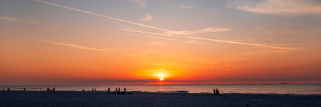 Beautiful sunset over the Baltic Sea. Silhouettes of people walking on the beach. Slajszewo, Polandの写真素材