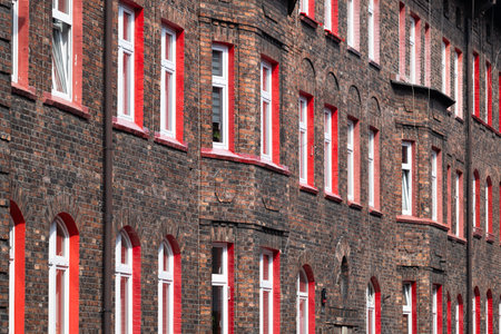 Red brick tenement house elevation. Red window frames. Old workers' housing estate. Unique...