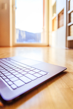Cutout of a modern laptop keyboard on the wooden floor with text spaceの写真素材