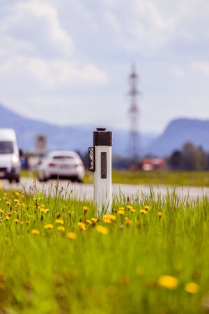 Reflector post and cars at an idyllic asphalted road in summer, flowers and green grassの写真素材