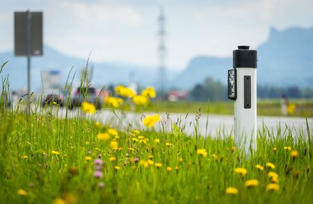Reflector post at an idyllic asphalted road in summer, flowers and green grassの写真素材