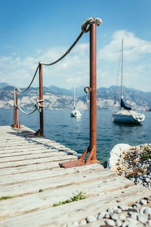 Compass lying on wooden dock pier in the foreground, sailing boats in the blurry backgroundの写真素材