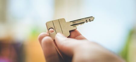 Holding a house key in the hand: New home and property.の写真素材