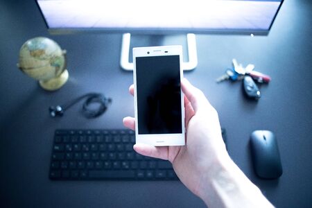 Web business: Smartphone in foreground. Computer, keyboard, credit card, compass, keys and globe in...