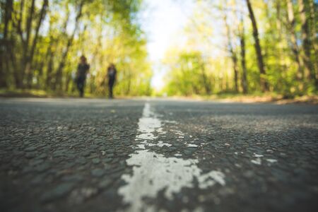 Asphalted street in the forest: Close up perspective, blurry backgroundの写真素材