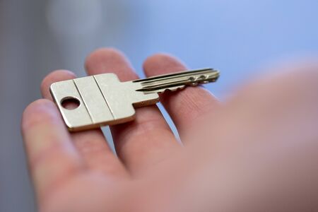 Holding a house key in the hand: New home and property.の写真素材