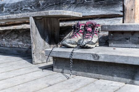 Close up picture of hiking boots on a rustic wooden veranda of an alpine hutの写真素材