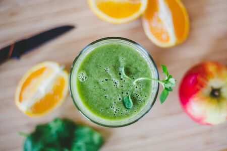Arrangement of a fresh green healthy smoothie and fruits on a wooden backgroundの写真素材