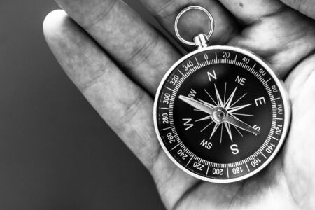 Closeup of a mans hand holding a compass in his hand. Concept for business, innovationの写真素材