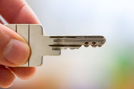 Holding a house key in the hand: New home and property.