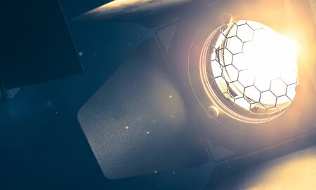 Professional orange studio spotlight hanging on the ceiling. Lighted dust particles and lens flares.の写真素材