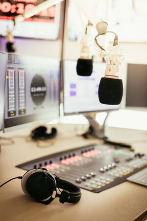 Studio microphone in a broadcasting radio studio, mixer and computer in the blurry background