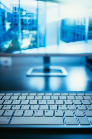 Freelancerâs workplace: Keyboard in the foreground, blurry screen in the backgroundの写真素材