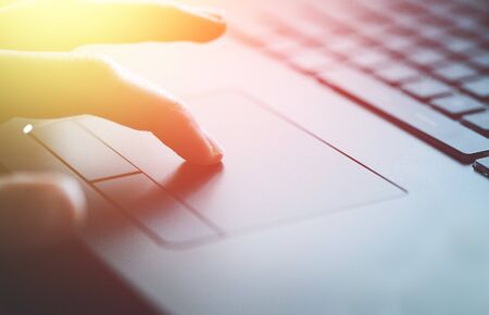 Close up picture of hands using a notebook touchpad, sunshineの写真素材