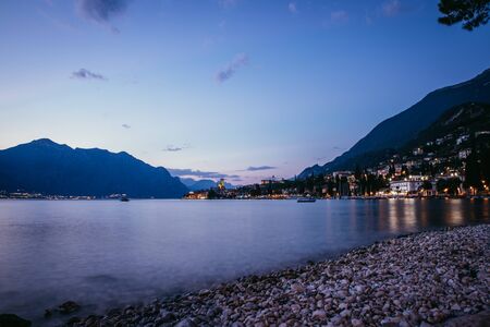 Beautiful evening scenery on the beach with cute little village, lago di garda, Italy. の写真素材