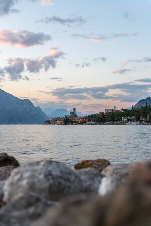 Beautiful evening scenery with cute little village, lago di garda, Italy. Stones in the foreground.の写真素材