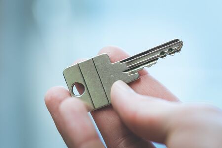 Holding a house key in the hand: New home and property.の写真素材