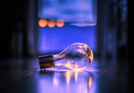 LED light bulb is lying on the wooden floor. Symbol for ideas and innovation. Window and light in the blurry background.の写真素材