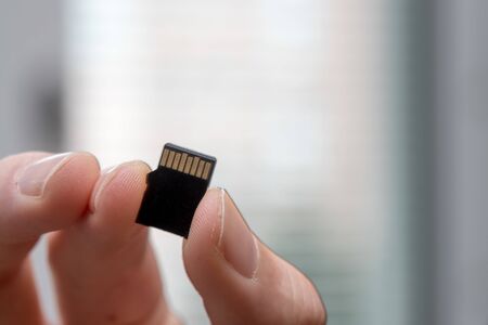 Young man is holding a tiny memory card in his hand, text spaceの写真素材