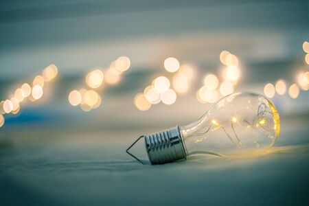 LED light bulb is lying in the bed. Symbol for ideas and innovation. Spot lights in the blurry background.の写真素材